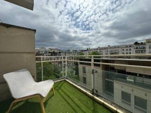 une chaise blanche assise au-dessus du balcon dans l'établissement Tres Bel Appartement 6P Terasse - Levallois, à Levallois-Perret