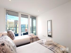 a bedroom with two beds and a large window at Deluxe Two Bed Apartment by London ExCeL & O2 in London