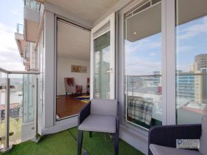 a balcony with a chair and a view of a city at Deluxe Two Bed Apartment by London ExCeL & O2 in London
