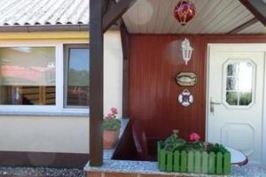 a house with a door and a porch with plants at Wunderschönes Ferienhaus in Altwarp mit Grill in Altwarp