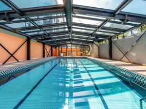 a large indoor swimming pool with a ceiling at Manhattan Porto Alegre by Mercure in Porto Alegre