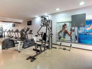 a gym with cardio equipment and a woman in a gym at Manhattan Porto Alegre by Mercure in Porto Alegre