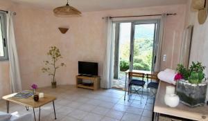 a living room with a couch and a tv at studio, vue sur mer et montagne in Saint-Florent