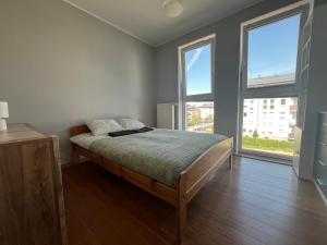 a bedroom with a bed and two large windows at Apartament Borkowo in Borkowo