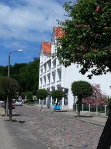 a white building with a red roof on a street at Ferienwohnung mit Balkon und Tiefgarage in Ostseebad Sellin