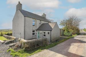 an old stone house with a green door on a road at Tregynrig Bach in Cemaes Bay