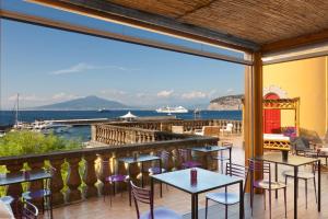 un patio con mesas y sillas y vistas al agua en Marina Piccola 73, en Sorrento