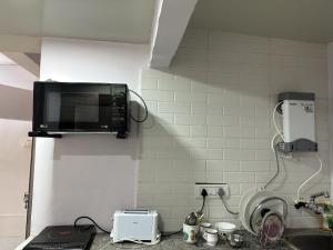 a microwave hanging on a wall in a kitchen at Ravish Apartment, Juhu in Mumbai