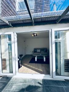 ein Wohnzimmer mit einer Couch durch eine Glasschiebetür in der Unterkunft Deluxe Bungalow in Longham + 6 Fotos