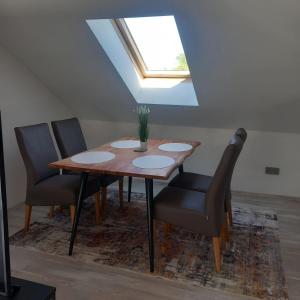 a dining room table with four chairs and a skylight at BlueLine Apartments am Wörthersee in Schiefling am See
