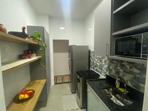 Il comprend une petite cuisine équipée d'un évier et d'une cuisinière. dans l'établissement Espaçoso apartamento reformado em Copacabana, à Rio de Janeiro