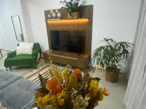 - un salon avec une télévision et des fleurs sur une table dans l'établissement Espaçoso apartamento reformado em Copacabana, à Rio de Janeiro