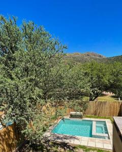 einen Pool in einem Garten mit Bäumen und einem Zaun in der Unterkunft MONTEARENA POTRERO DE LOS FUNES in Potrero de los Funes