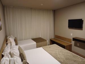 um quarto de hotel com duas camas e uma televisão de ecrã plano em Laghetto Golden Resort em Gramado