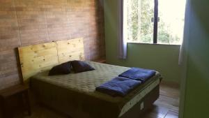 um quarto com uma cama com uma cabeceira em madeira e uma janela em Aconchegante Casa em São Lourenço