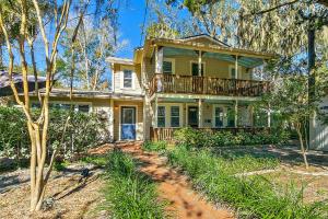 una casa gialla con balcone e alberi di Cozy Uptown Guest House a St. Augustine