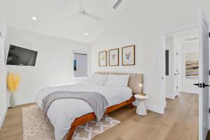 a white bedroom with a bed and a flat screen tv at 196 Riberia - Downtown Waterfront Luxury Home in Saint Augustine