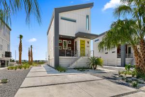 a white building with a yellow door and palm trees at 200 Riberia - Downtown Waterfront Luxury Home in St. Augustine
