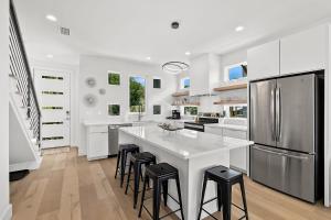 een witte keuken met een wit eiland en zwarte krukken bij 198 Riberia - Downtown Waterfront Luxury Home in St. Augustine