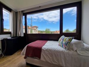 sypialnia z łóżkiem i dużym oknem w obiekcie Apartamento en Poo de Llanes w mieście poo de Llanes