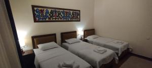 a room with three beds and a painting on the wall at Green House ECO HOTEL in Samarkand
