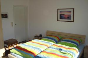 a bed with colorful blankets on it in a bedroom at Komfortable Ferienwohnung mit großem Garten in Lütjendorf