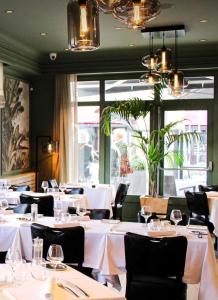 a restaurant with white tables and chairs and a window at Hotel Restaurant du Centre et du Lauragais in Castelnaudary