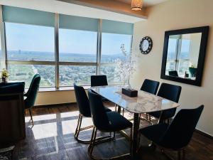a dining room with a table and chairs and a clock at Centaurus Apartment in Islamabad