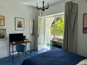 a bedroom with a bed and a desk and a window at Villa Striano Capri in Capri