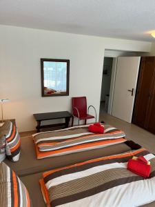 een slaapkamer met 2 bedden en een rode stoel bij Tulai D74 in Scuol