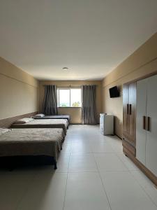 een hotelkamer met 3 bedden en een raam bij Apartamento no Centro do Cumbuco in Cumbuco