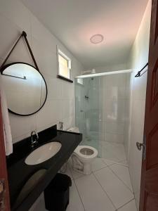 een badkamer met een wastafel, een toilet en een spiegel bij Apartamento no Centro do Cumbuco in Cumbuco