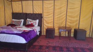 a bedroom with a bed and a table at camp erg znaigui in Taouz