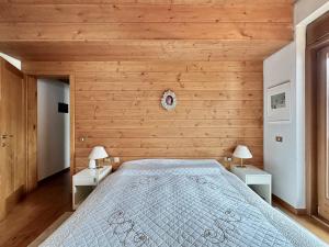 a bedroom with wooden walls and a bed with two tables at Classy 4 bedroom few steps from centre in Cortina dʼAmpezzo
