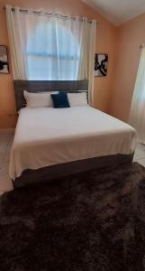een slaapkamer met een groot wit bed en een raam bij Caribbean Estate Vacay Stay 3 in Portmore