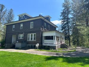 a large brown brick house with a porch at The Manor at Glen Jean Meadows in Oak Hill