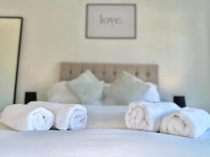 a pile of towels sitting on top of a bed at Long Term Comfort - Modern 3BR Retreat with Free Parking & WiFi in Enfield Lock