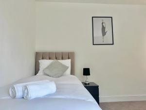 a white bed with two towels on top of it at Long Term Comfort - Modern 3BR Retreat with Free Parking & WiFi in Enfield Lock