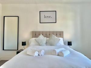 um quarto com uma cama branca e toalhas em Long-Term Comfort - Modern 3BR Retreat with Free Parking & WiFi em Enfield Lock