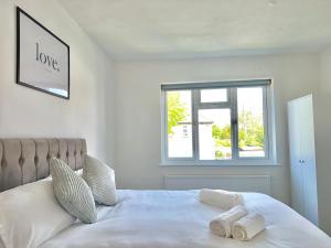 a bedroom with a white bed with two towels on it at Long Term Comfort - Modern 3BR Retreat with Free Parking & WiFi in Enfield Lock