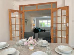 a table with glasses and a vase of flowers on it at Long Term Comfort - Modern 3BR Retreat with Free Parking & WiFi in Enfield Lock