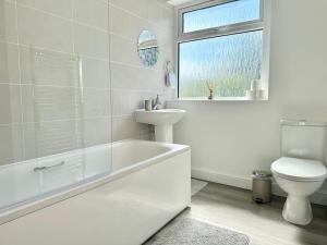 Baño blanco con aseo y lavamanos en Long-Term Comfort - Modern 3BR Retreat with Free Parking & WiFi en Enfield Lock