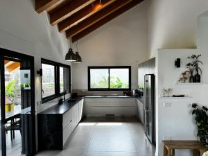 une cuisine avec des murs blancs et un comptoir noir dans l'établissement Gilboa cliff eclectic villa- heated swimming pool, à Nurit