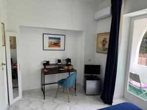 a room with a desk with a blue chair and a window at Villa Striano Capri in Capri