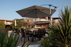 um pátio com uma mesa, cadeiras e um guarda-sol em Calamadonna Club Hotel em Lampedusa