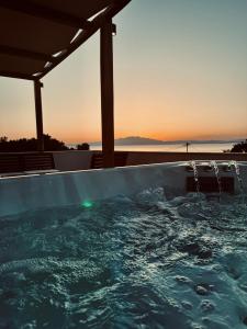 a hot tub with the sunset in the background at Villa Emilia Suites in Pachis