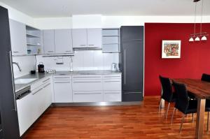 una cocina con armarios blancos y una pared roja en Chasa Miramunt 4, en Scuol