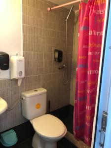 La salle de bains est pourvue de toilettes et d'un rideau de douche rose. dans l'établissement S&K Dotro, à Costinesti