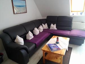 a black couch with white pillows sitting in a living room at Moderne Ferienwohnung mit Balkon in Strandnähe in Friedrichskoog