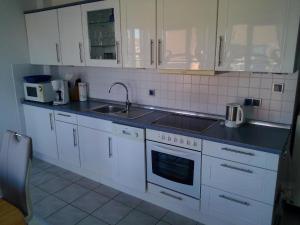 a kitchen with white cabinets and a sink at Moderne Ferienwohnung mit Balkon in Strandnähe in Friedrichskoog